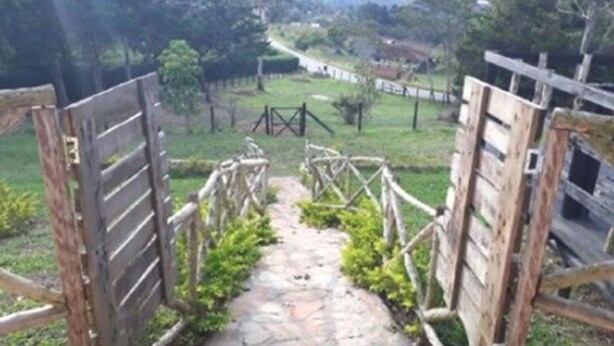 Une porte en bois rustique qui mène à un sentier de pierres, bordé de verdure.