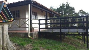 Un bâtiment avec un toit en tuiles, une terrasse en bois et un banc.