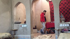A room with arched doorways, a patterned carpet, and a red tablecloth. - Zaid House (Taouz)
