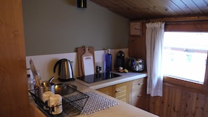 A kitchen with wooden cabinets, a sink, a kettle, a toaster, and a window with curtains. - Apartment Mola 19 (Arinsal)