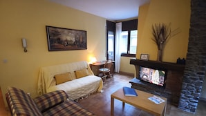 Una sala de estar con un sofá, una mesa de centro, una chimenea y un cuadro en la pared.