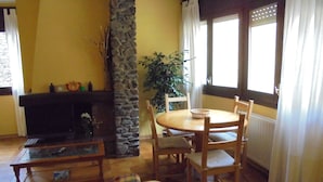 Una sala de estar acogedora con chimenea, muebles de madera y un amplio ventanal con cortinas.