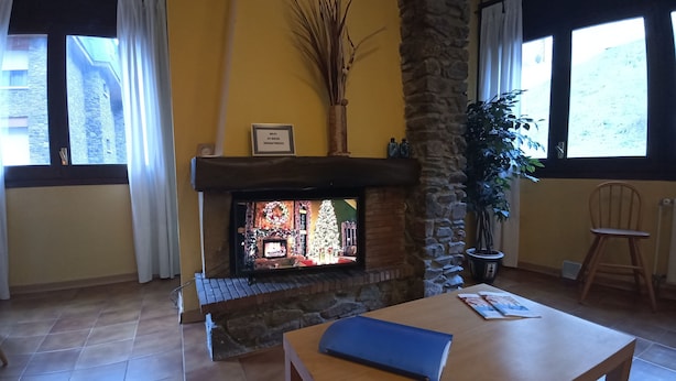 Una sala de estar con chimenea, un pilar de piedra, una mesa de madera y una planta en maceta.