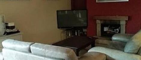 Una sala de estar con un sofá, un televisor y una chimenea.