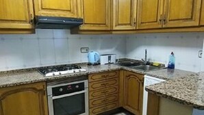 A kitchen with wooden cabinets, a gas stove, an oven, and a sink. - Apartment Abella 25 (Arinsal)