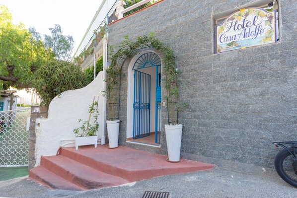 Un edificio de piedra con puerta azul y un letrero que dice 'Hotel Casa Adolfo'.