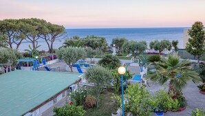 A coastal resort with a pool area, outdoor seating, and a view of the sea.