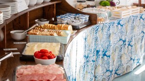 A buffet with various food items including bread, cheese, tomatoes, and meats.