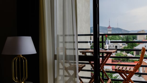 A balcony with a table, chairs, and a lamp. - Rivendell Umbrella Collections  (Tbilisi)