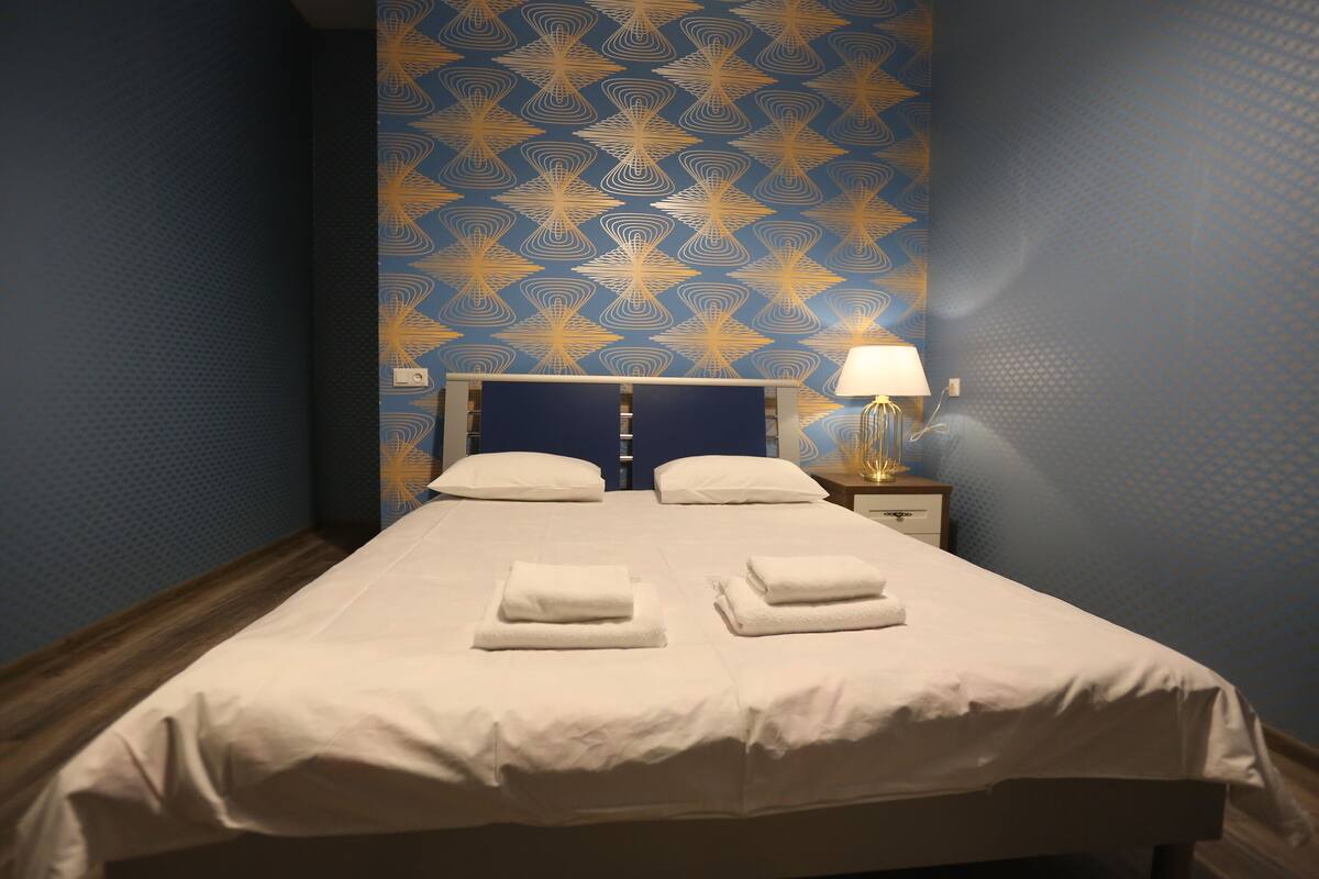 A neatly made bed with white linens and two folded towels on the bed.