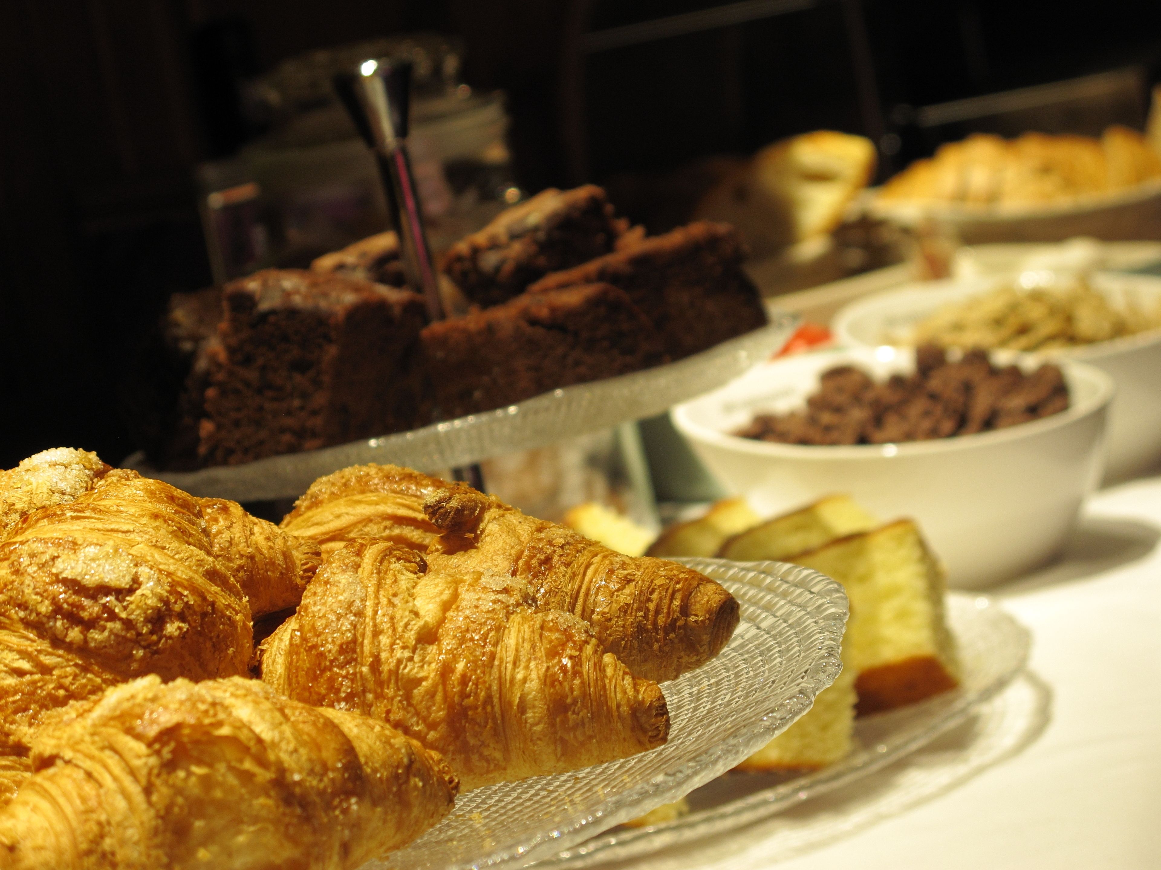A buffet with various baked goods including croissants and brownies.