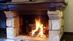 A stone fireplace with a wooden mantel and a glass candle holder. - Pèira Blanca Hotel Gastronómico (Naut Aran)