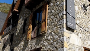 A stone building with a wooden balcony and a sign indicating it is a hotel. - Pèira Blanca Hotel Gastronómico (Naut Aran)