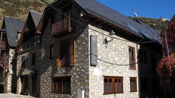 Un bâtiment en pierre doté d’un balcon, une enseigne indiquant qu’il s’agit d’un hôtel, et une vue sur les environs.
