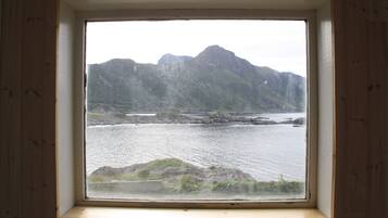 Una ventana con vista a una cadena montañosa y un cuerpo de agua.