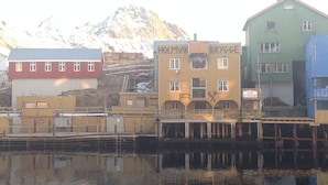 A waterfront building with multiple stories, featuring a restaurant sign and a visible staircase. - Holmvik Brygge Nyksund (Oksnes)