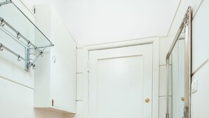 A narrow hallway with a wooden dresser, a glass shower enclosure, and a white door. - 4Culture Apart (Lodz)