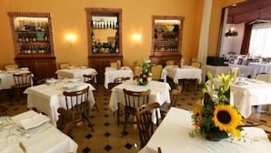 Un espace repas avec des tables dressées, un sol carrelé et un mur en briques agrémenté d’un miroir.