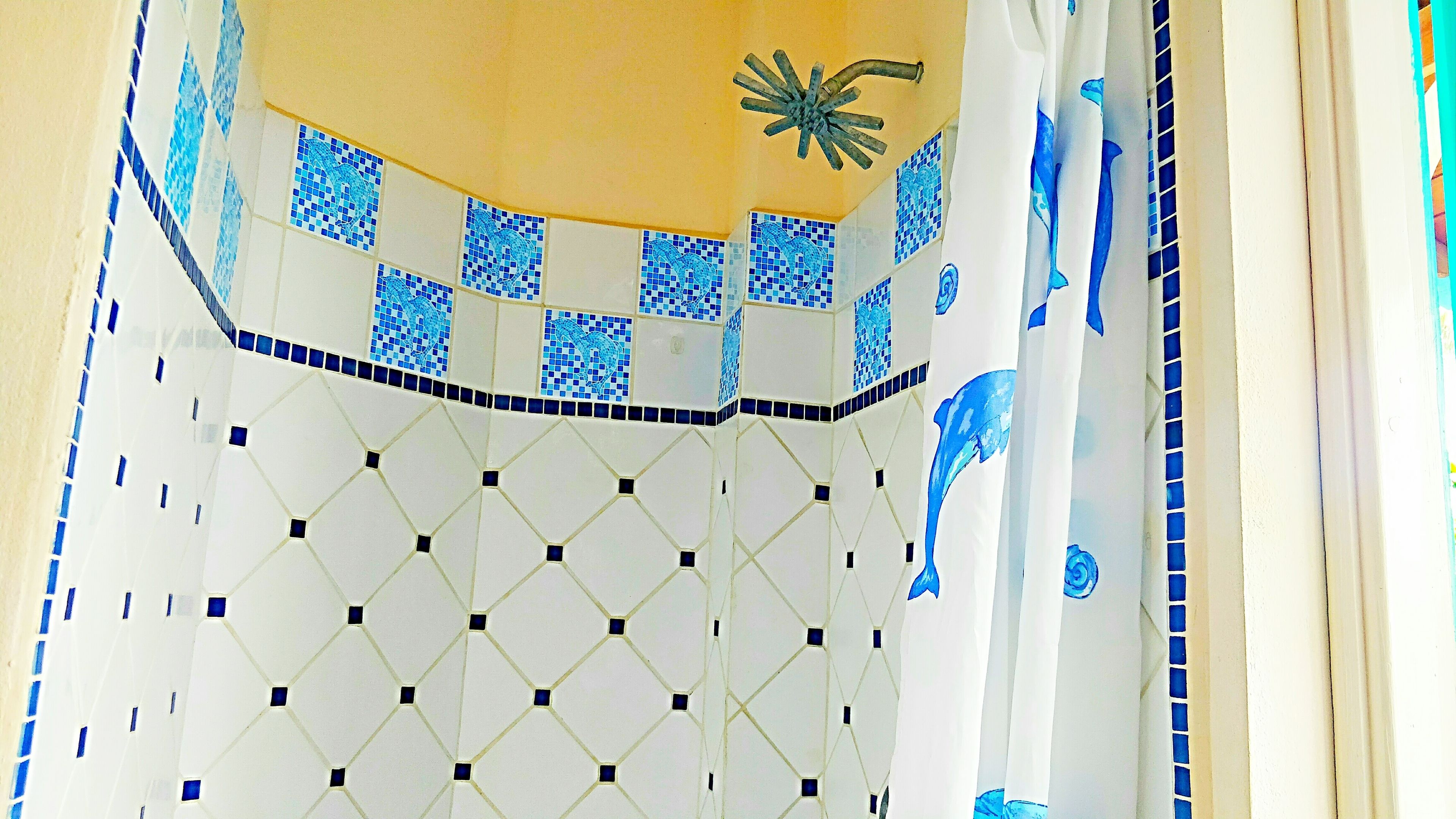 Un mur recouvert de carreaux formant un motif géométrique, avec des touches de bleu.