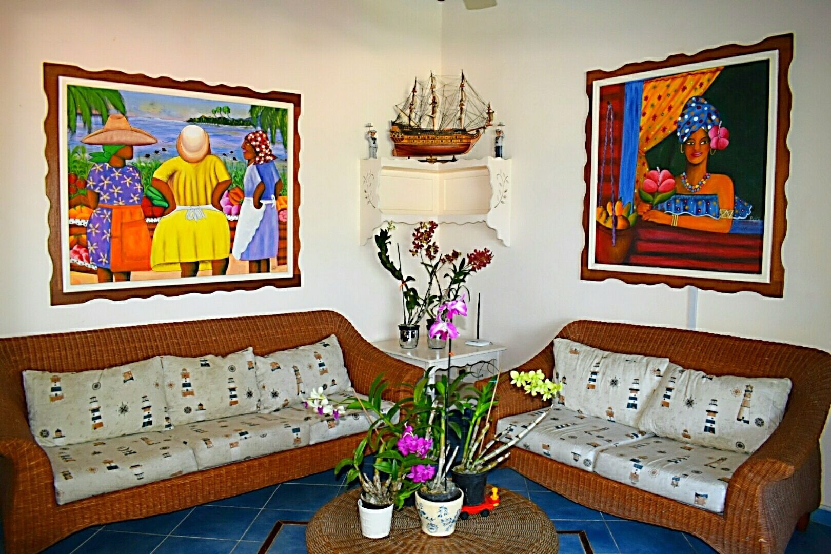 A living room with two sofas, a coffee table with plants, and two framed artworks on the walls.