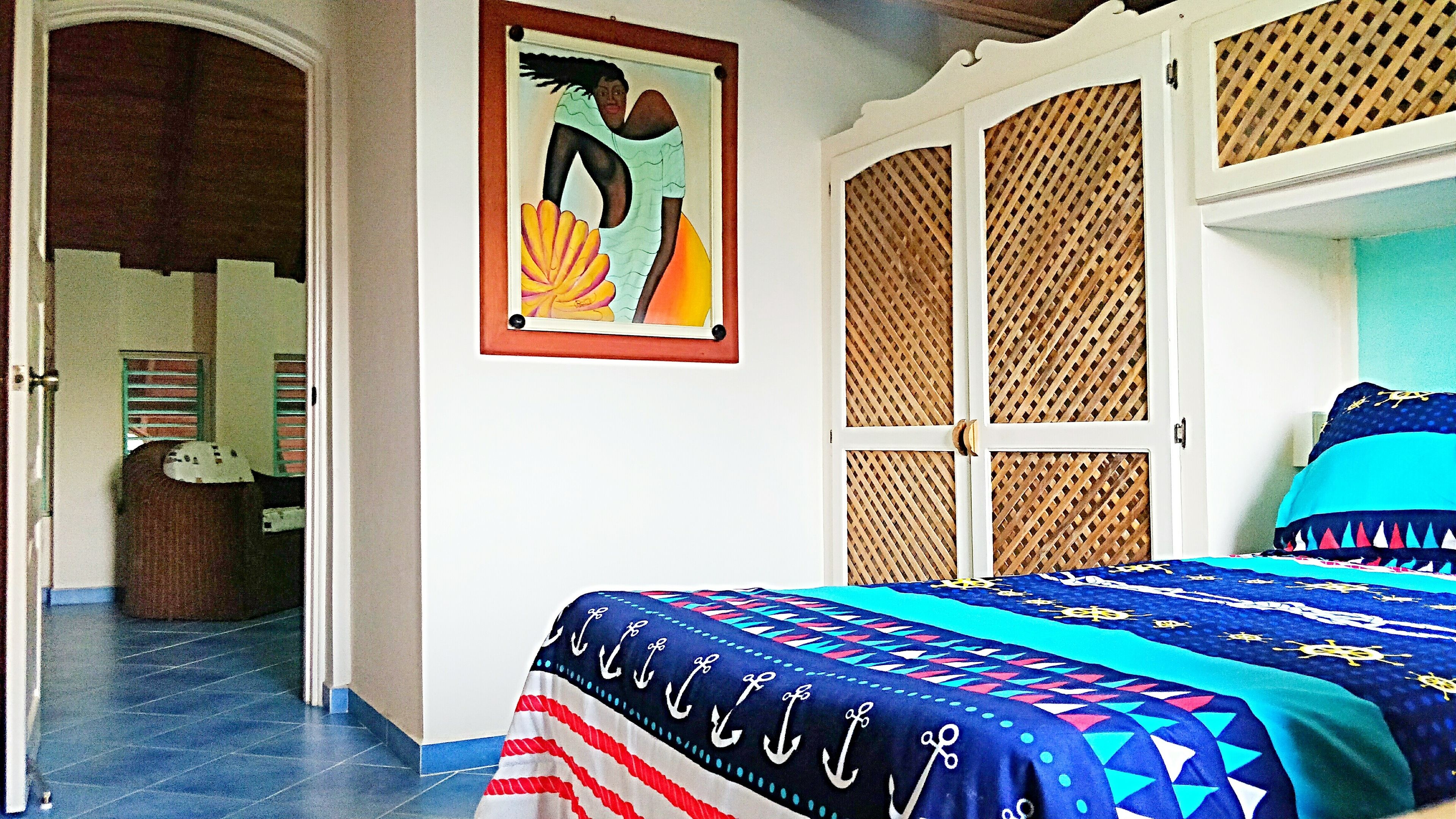 Un dormitorio con cama, un cuadro y una puerta que da a otra habitación.