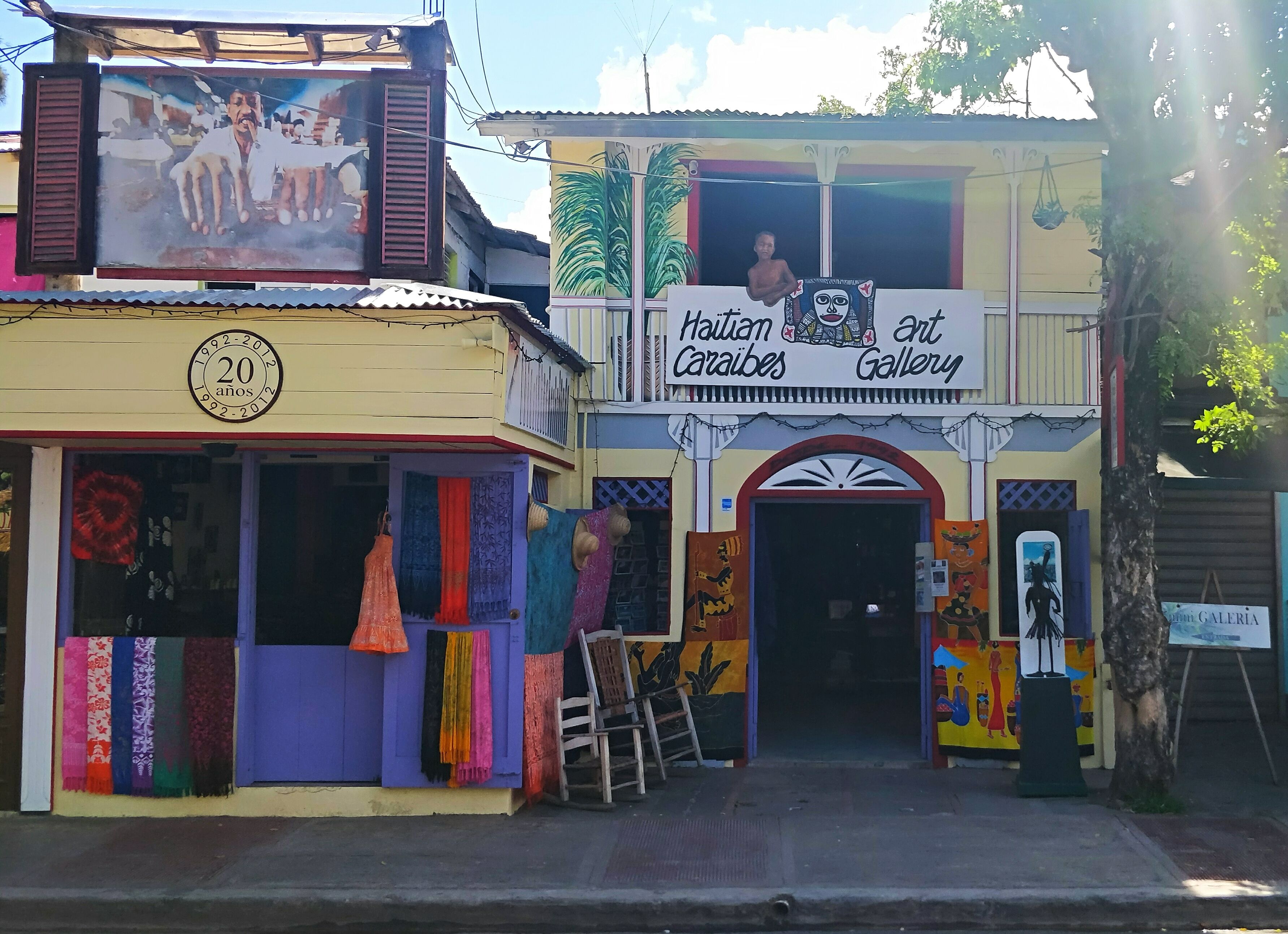 A building with a sign for 'Haitian Art Gallery' and a '20 years' celebration plaque.