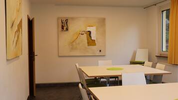 A conference room with a large table, white chairs, and a painting on the wall.