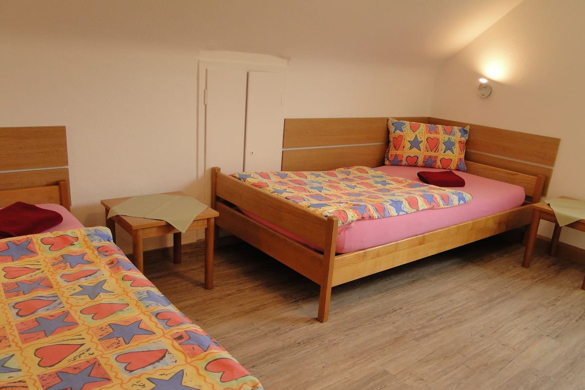 A bedroom with a wooden bed, a wooden desk, and a chair.