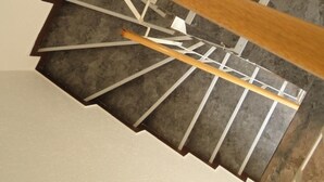 Een wenteltrap met houten leuning en witte wanden.