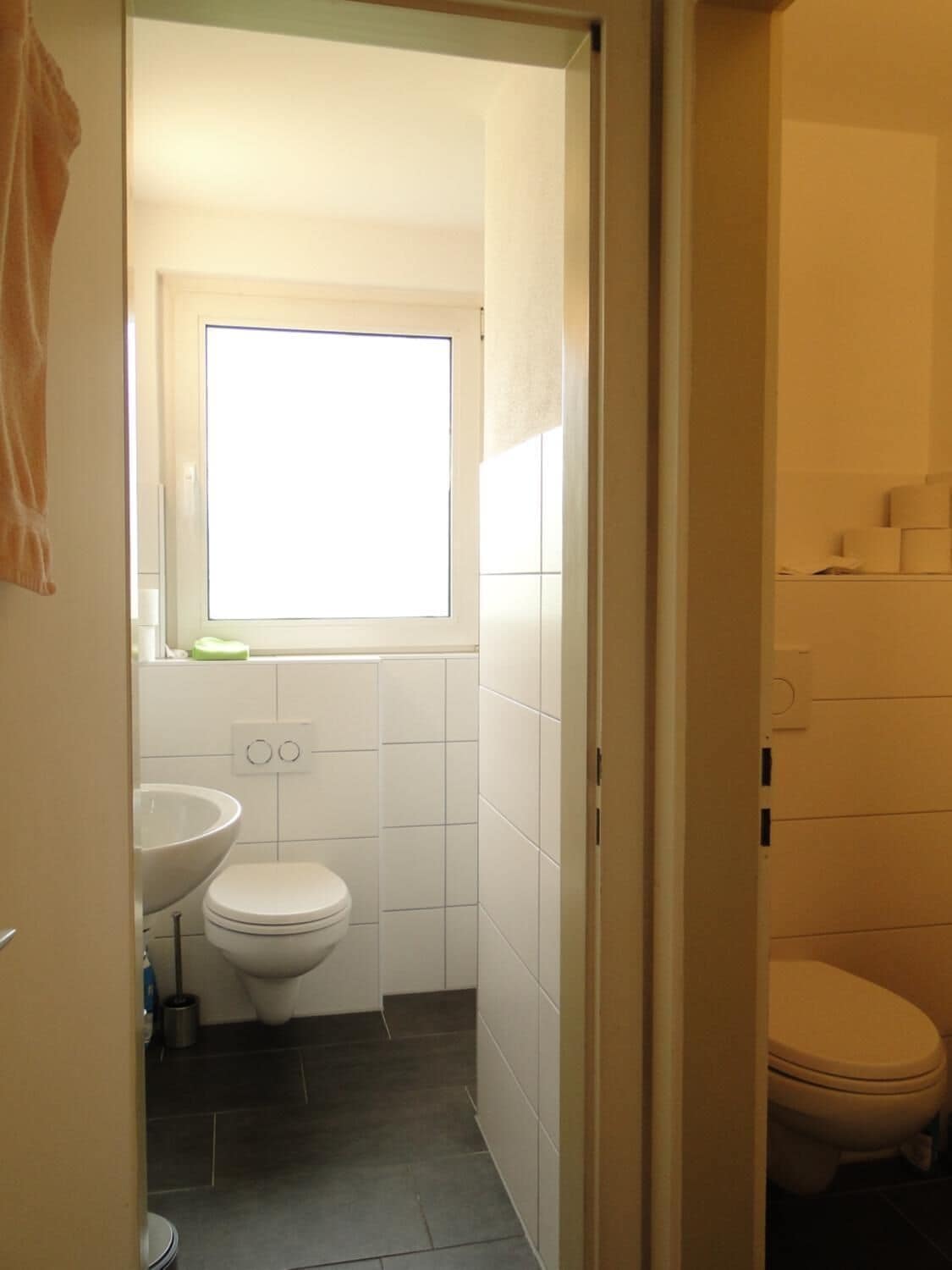 Une petite salle de bain avec des toilettes, un lavabo et une fenêtre.