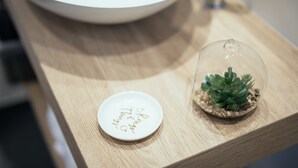 Ein Holztisch mit einer Glaskuppel, darin eine Sukkulente und ein weißer Teller mit handgeschriebenem Text.