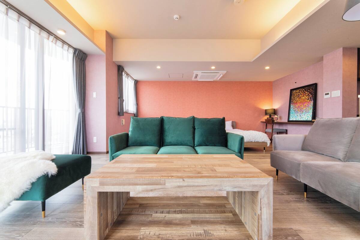 A modern living room with a green sofa, a grey sofa, and a wooden coffee table.