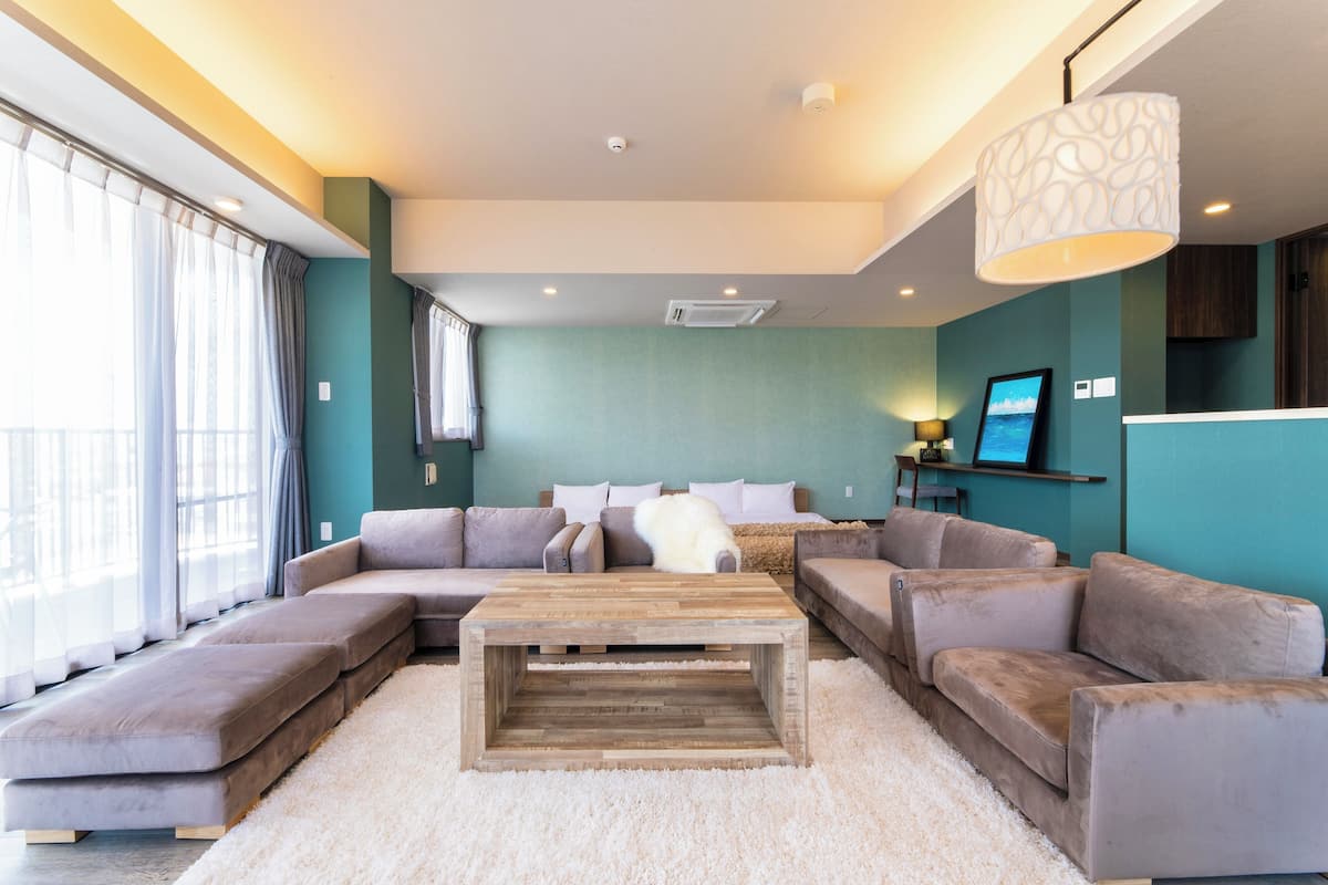 A modern living room with a sectional sofa, a wooden coffee table, and a large window with curtains.