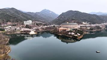 A hotel with a central building surrounded by a lake, with mountains in the background.