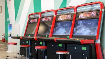 Cuatro máquinas de videojuegos de arcade con marcos rojos y mangos verdes, cada una con una pantalla mostrando gráficos de juego.