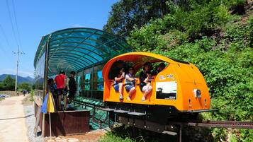A small, enclosed train car with passengers seated inside, parked next to a covered walkway.