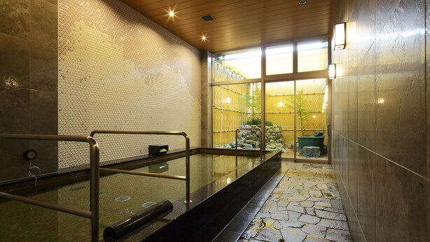Uma área de spa com hidromassagem em vidro, teto de madeira e piso de pedra.
