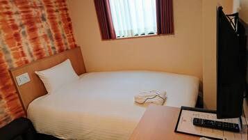 Une chambre d’hôtel avec un lit, une table de chevet avec une télécommande et une fenêtre avec des rideaux.