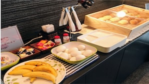 Um buffet de café da manhã com diversos alimentos, incluindo ovos, bananas e pão.