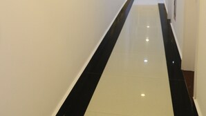 A hallway with white walls, a black and white floor, and a ceiling with recessed lighting. - Arapang Hotel 2 (Xuan Huong - Da Lat)