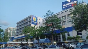 A hospital building with multiple floors, a parking lot, and several trees in front. - Venice Resort (Lam Luk Ka)