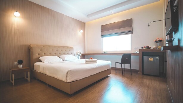 A modern bedroom with a large bed, bedside table, and a small desk area. - Venice Resort (Lam Luk Ka)