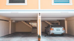 A parking garage with a car parked in the middle. There is a staircase leading to an upper level. - Venice Resort (Lam Luk Ka)
