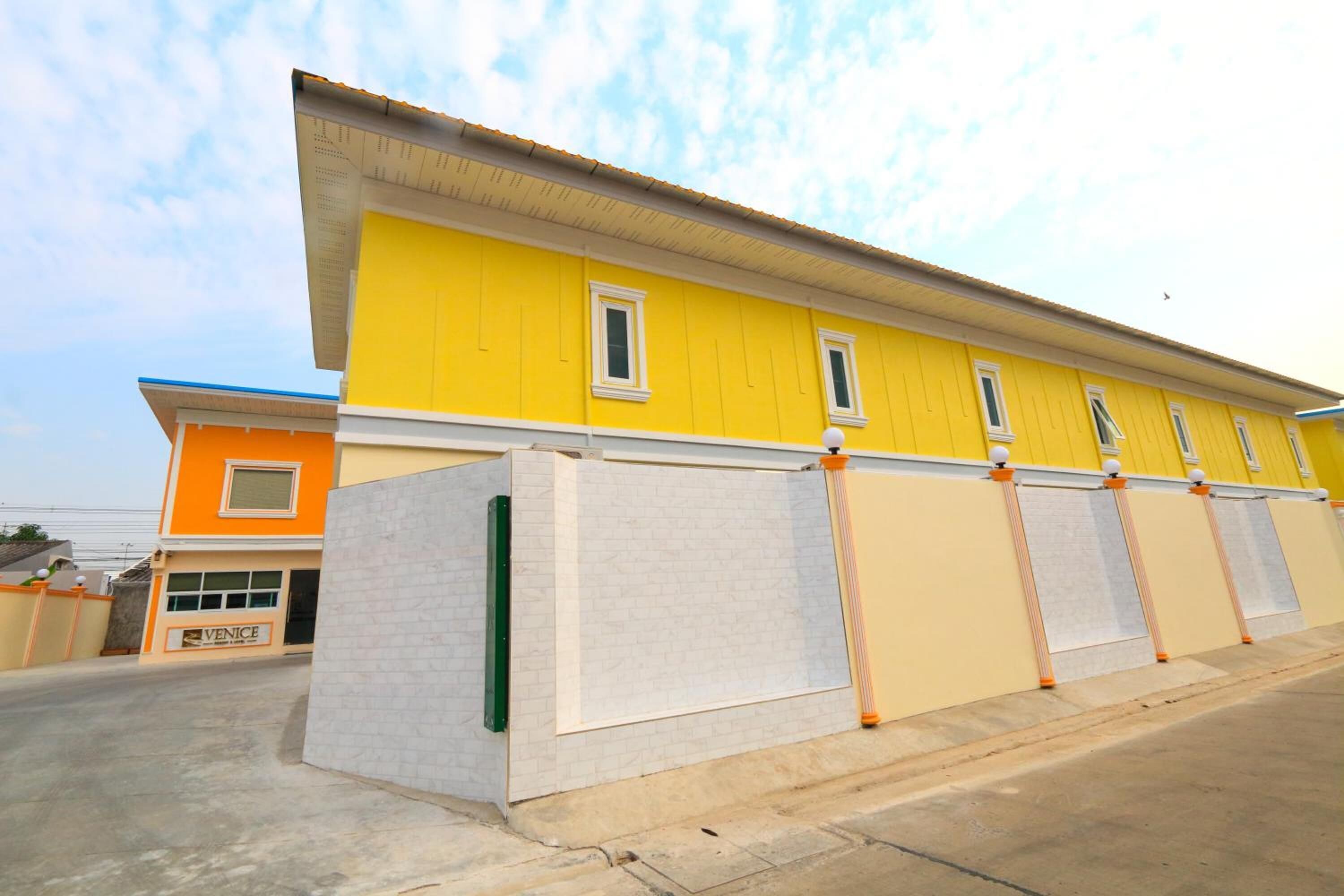 A yellow building with a garage door and a sign that reads "VENICE".