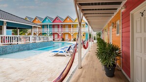 A pool area with lounge chairs and a hammock, surrounded by colorful buildings with balconies. - Bed & Bike Curacao - Jan Thiel (Jan Thiel)