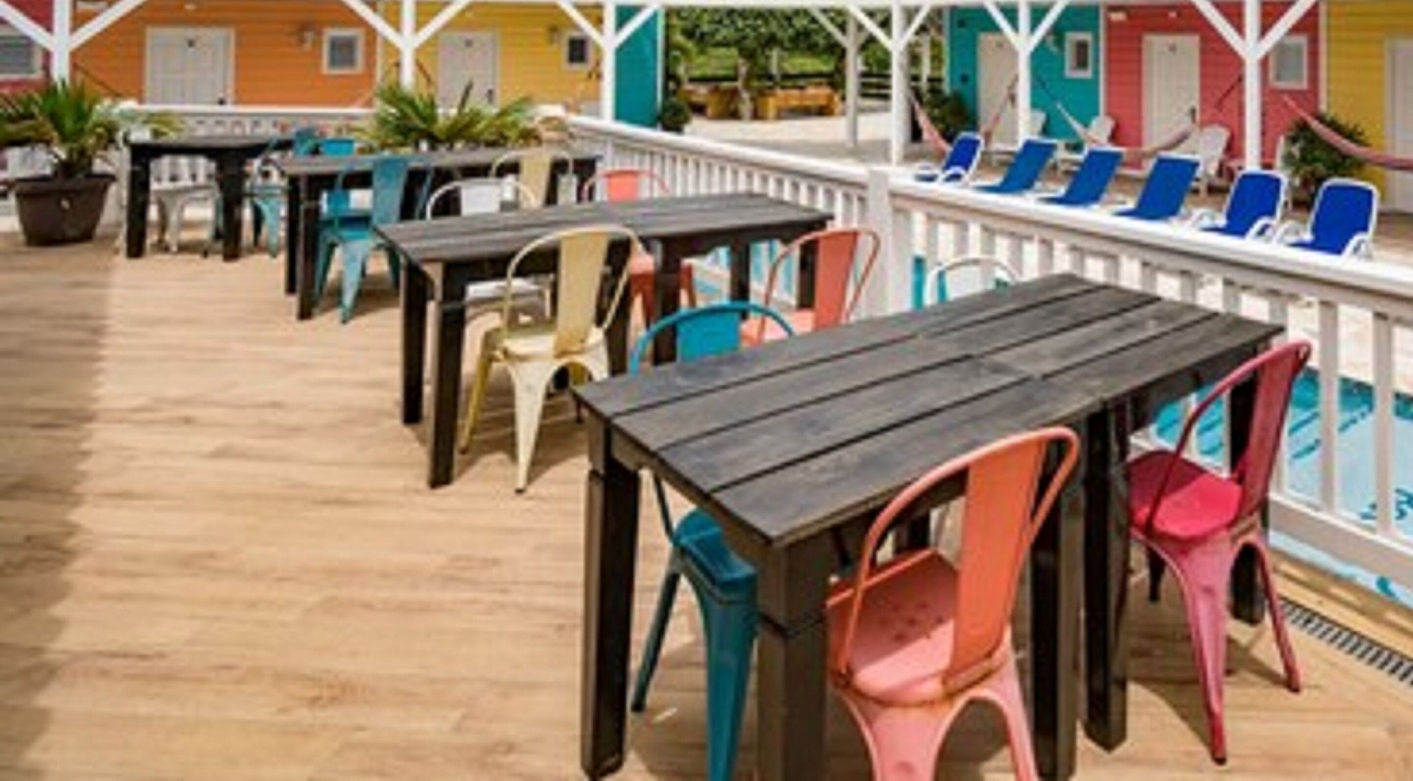 A deck with outdoor seating, including tables and chairs, overlooking a pool area.