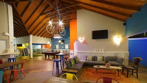 A spacious indoor area with a wooden ceiling, a sofa set, a billiards table, and a dining area with stools and a table. - Bed & Bike Curacao - Jan Thiel (Jan Thiel)