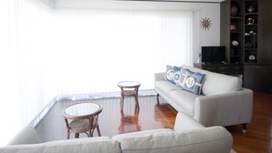 A living room with a white sofa, a small round table, and a television. - Pontoon (Ishigaki)