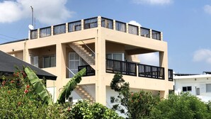 A two-story building with a balcony on the upper floor, a satellite dish, and a staircase leading to the upper level. - Pontoon (Ishigaki)