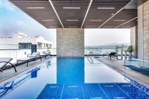 A rooftop infinity pool with clear blue water, surrounded by lounge chairs and a glass railing. - Emerald Bay Hotel & Spa Nha Trang (Nha Trang)